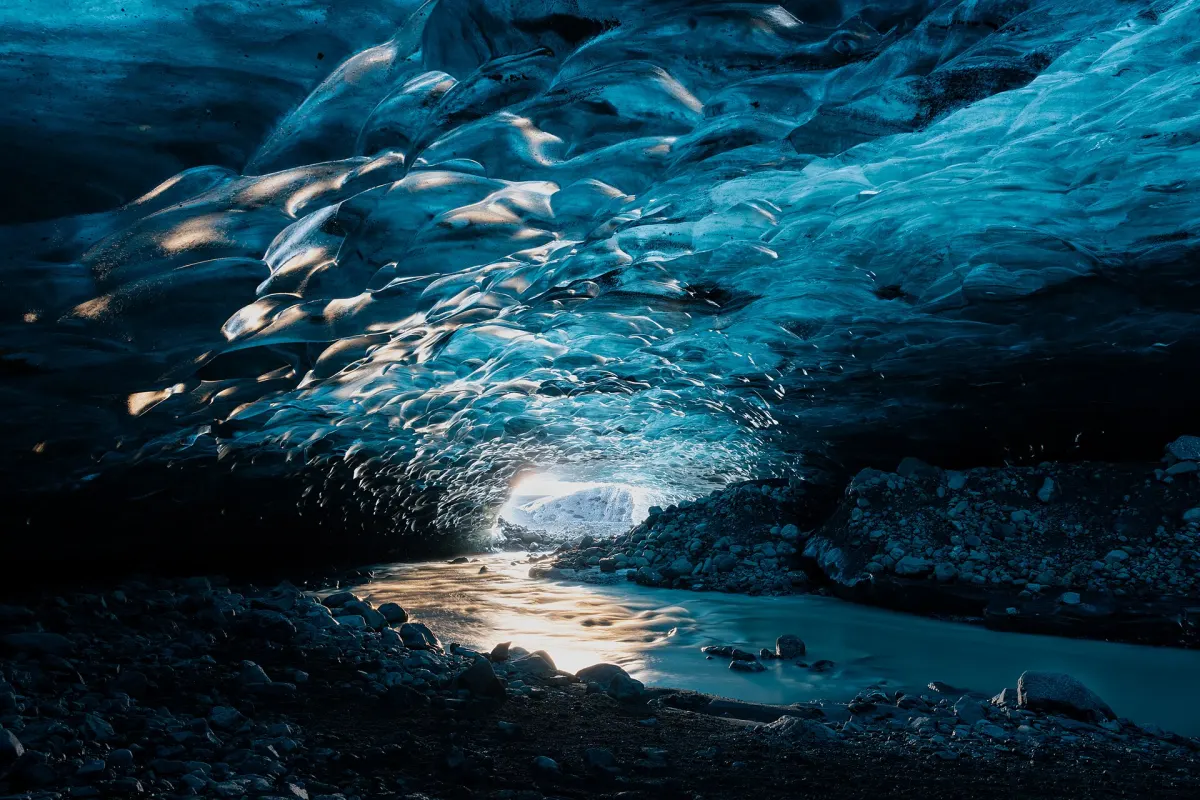 Blick in eine natürliche blaue Eishöhle nahe der Gletscherlagune Jökulsárlón, Tageslicht scheint durch das Eis